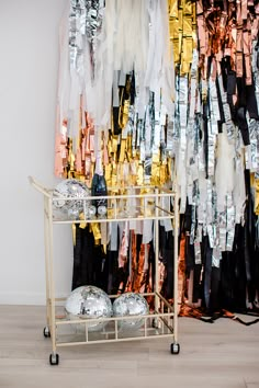 a gold and black rack with shiny clothes hanging on it's sides in front of a white wall