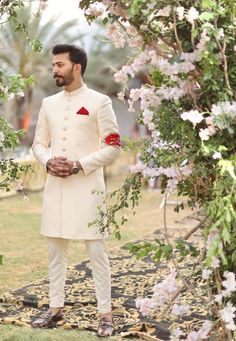 a man in a white suit standing under a tree