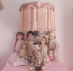 a lamp that is on top of a table with many dolls and teddy bears around it