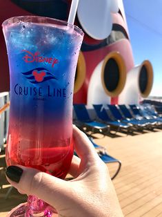 someone holding up a drink in front of the disney cruise ship