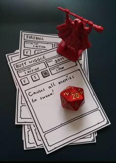 a red dice sitting on top of some white paper next to a small toy figure