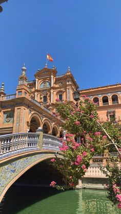 a bridge over a body of water in front of a building with flowers on it