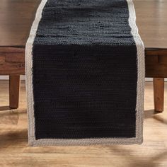 a black and white knitted table runner on a wooden table with two chairs in the background