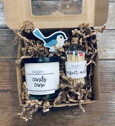 an open box with matches, candle and bird magnets in it on a wooden table