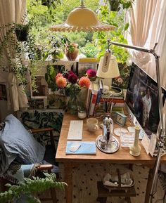 a desk with a computer on it and lots of plants