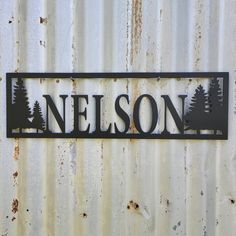 a metal sign that says nelson on it's side with trees in the background