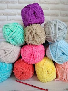 multicolored balls of yarn sitting on top of each other next to a knitting needle