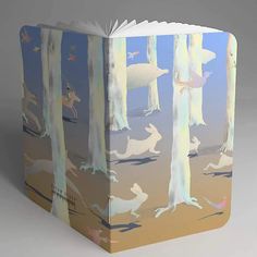 an open book with animals and trees on the cover, in front of a gray background