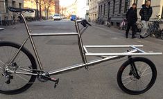 a silver bike parked on the side of a street next to people walking down it