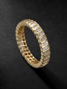 a yellow gold ring with white diamonds on black background, close up view from the side