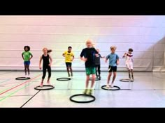 a group of people standing on top of hoop rings in a gym floor with one person holding a microphone