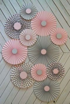 paper fans are arranged on the floor in different shapes and sizes, including pinks and greys