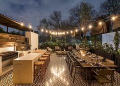 an outdoor dining area is lit up at night with string lights strung from the ceiling