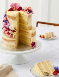 a three layer cake sitting on top of a table next to plates with slices cut from it