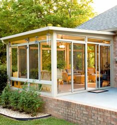 an enclosed patio with glass walls and brick steps leading up to the back of the house