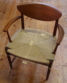 a wooden chair with a measuring tape on it's back and seat, sitting on a hard wood floor