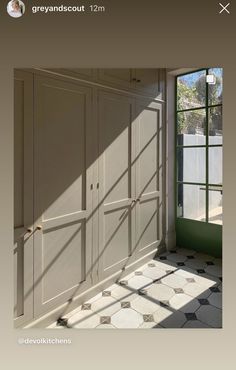 an empty room with green doors and white cabinets in front of a large open window