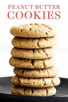 a stack of peanut butter cookies sitting on top of a black plate next to a white background