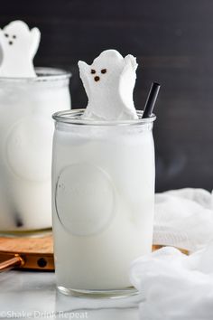 two glasses filled with white liquid and marshmallows in the shape of ghostes