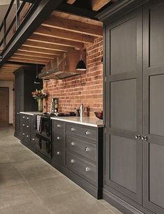 a kitchen with black cabinets and brick walls