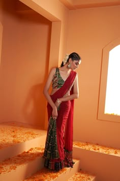 Introducing our striking Red Lehriya Drape Saree with Artsilk Bandhani and Shell detailing, accompanied by a Green Print Bandhani Blouse adorned with Shells and Fringes – a captivating ensemble that seamlessly merges traditional aesthetics with contemporary charm. Blouse On Bandhani Saree, Contemporary Saree Look, Red Saree Design, Bandhani Aesthetic, Lehariya Saree Blouse Design, Lehriya Saree Blouse Designs, Blouse Designs For Bandhani Sarees, Red Saree Green Blouse, Paithani Saree Blouse Pattern