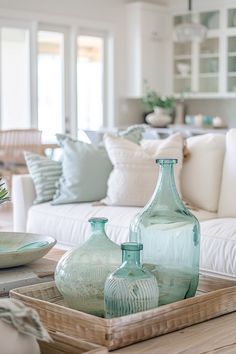 a tray with vases sitting on top of a wooden table next to a couch