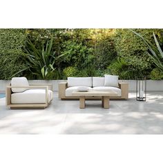 an outdoor living room with white furniture and greenery