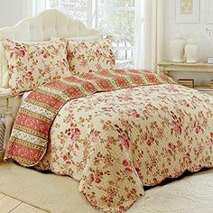 a bed with floral comforter and pillows on top of it in front of a window