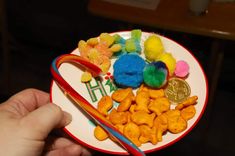 a person holding a plate with different colored candies on it and a gold coin