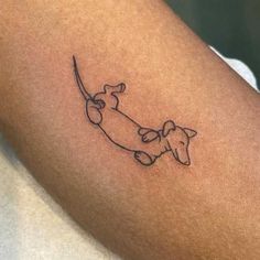 a small tattoo of a dog on the arm with a long tail that is curled up to it's neck