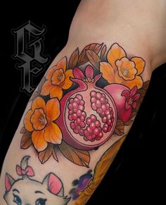 a woman's arm with flowers and pomegranates on it