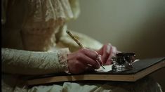 a woman in white dress writing on a book with a pen and quill - pen