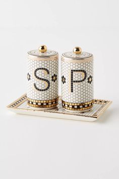 two salt and pepper shakers on a tray with the letter p spelled in gold