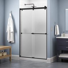 a bathroom with blue walls and white towels hanging on the shower door, along with a wooden bench