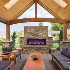 an outdoor living area with couches and a fireplace in the center surrounded by wood beams