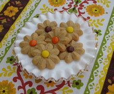 a white plate topped with cookies on top of a colorful table cloth covered in flowers