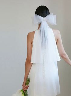 a woman in a white dress with a veil on her head and flowers in her hand