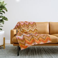 a couch with a blanket on it next to a potted plant