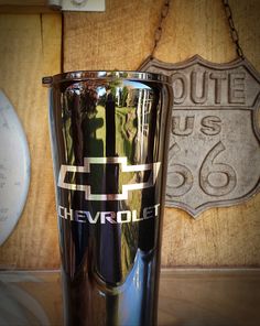 a metal cup sitting on top of a wooden table next to a sign that says route 66