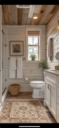 a white bathroom with wood paneling and a rug on the floor next to the toilet