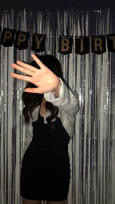 a woman standing in front of a curtain with her hand up to her face and the words happy birthday on it