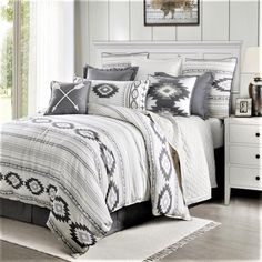 a white bed sitting next to a window with pillows on top of the bedspread