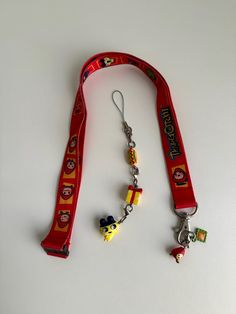 a lanyard with charms attached to it on a white surface and the lanyard is red