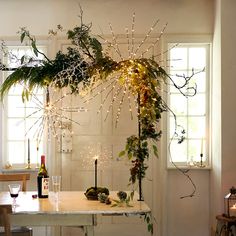 a dining room table covered in greenery and lights