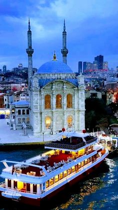 a large boat floating on top of a river next to a tall building with spires