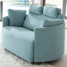 a light blue chair sitting in front of a window with a white rug on the floor