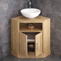 a bathroom with a sink and wooden cabinet in it's corner, next to a tiled wall