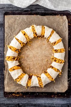 a cake that is sitting on top of a piece of wax paper with some shredded cheese around it