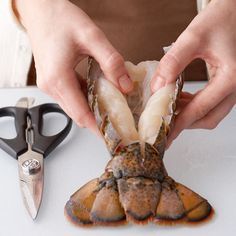 a person cutting up some food on top of a white table next to scissors and a pair of shears