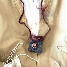 a crocheted bag with a button on the front is hanging from a cord